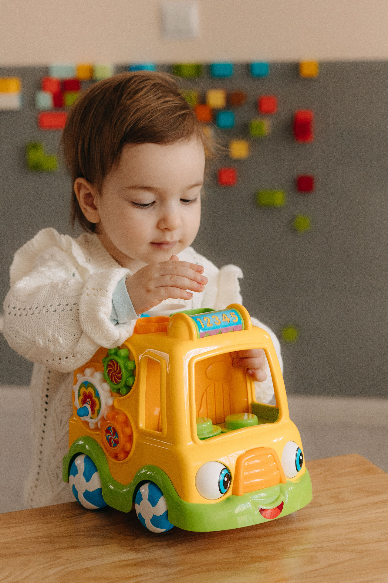 Toddler exploring a colourful toy bus at Little Steps Academy